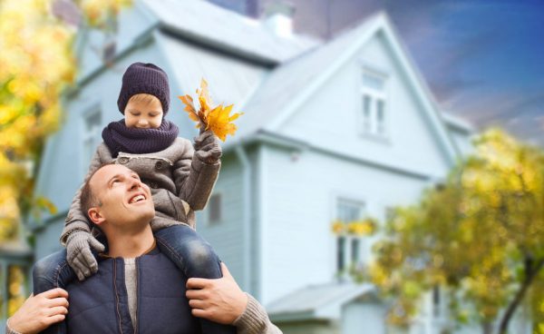 father and son with autumn maple leaves over house