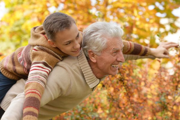 Portrait of grandfather and grandson hugging in park