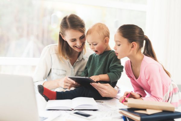 A woman works during maternity leave at home. A woman works and cares for a children at the same time.