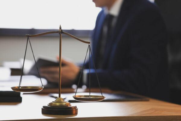 Scales of justice and blurred lawyer on background