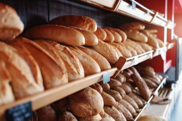 Fresh delicious loafs of bread in row on shelves ready for sale. Bakery interior.