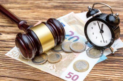 Judge's gavel with euro and clock on the wooden table.