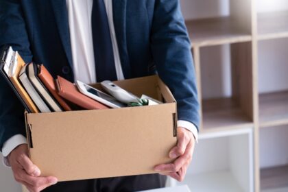 Sad Fired Young Employee businessmen hold boxes including pot pl