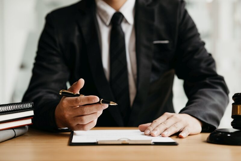 A lawyer sits in his office, on a table with a small hammer to b