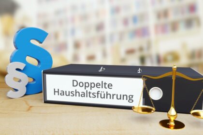 Doppelte Haushaltsführung – Gesetz/Recht. Ordner auf Schreibtisch mit Beschriftung neben Paragraf und Waage. Anwalt