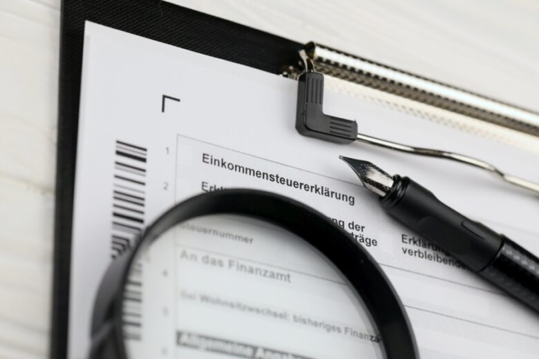 German annual income tax return declaration form blank on A4 tablet lies on office table with pen and magnifying glass