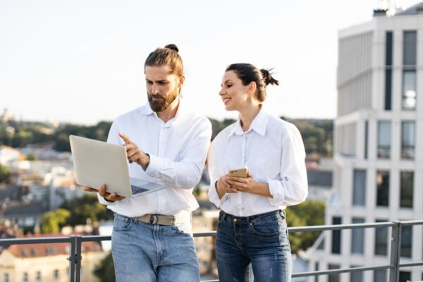 Colleagues discussing project with laptop on rooftop