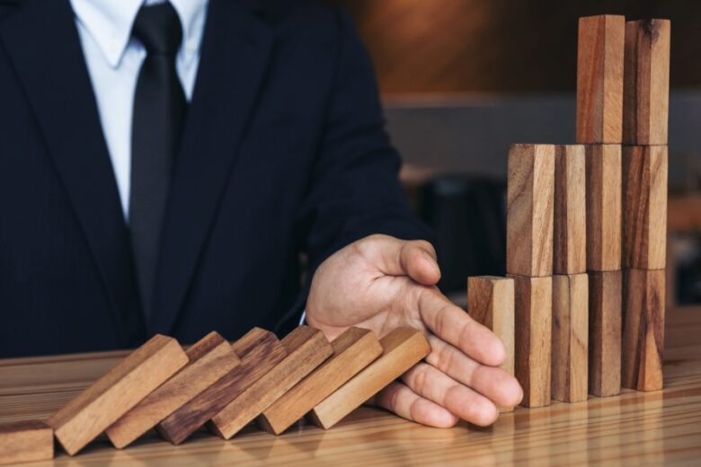 Close up of businessman hand Stopping Falling wooden Dominoes ef